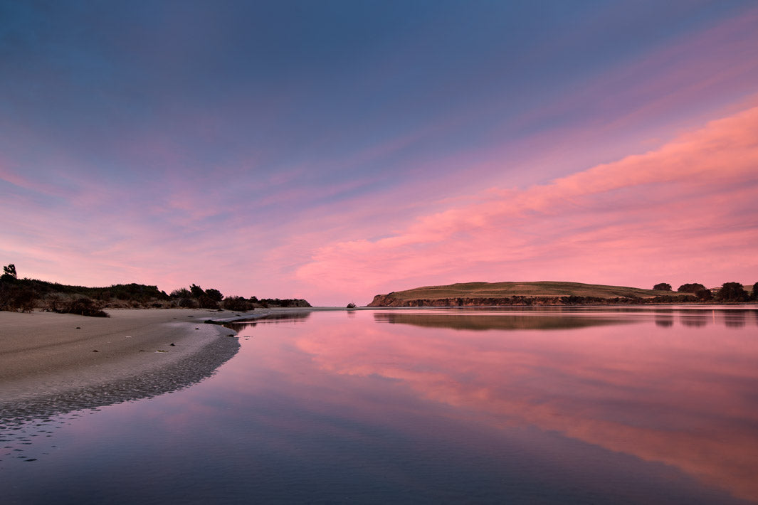 Pink and blue skies at sunrise reflected in the sea below