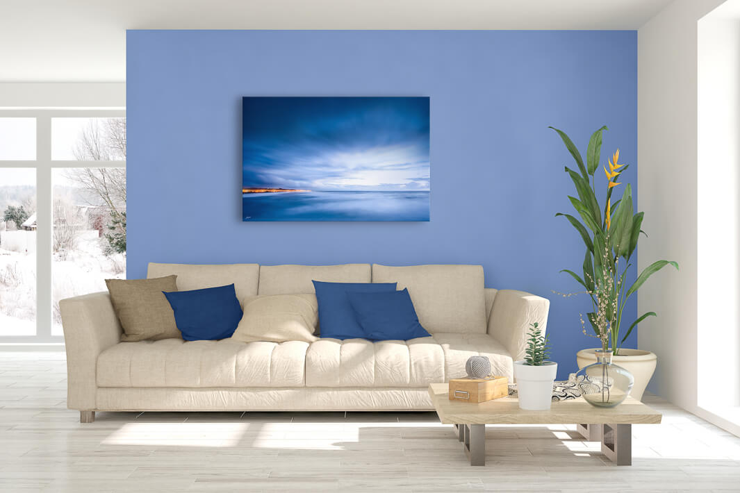 New Zealand landscape photo canvas wall art in lounge setting with blue wall, a white couch, cushions, coffee table and plant