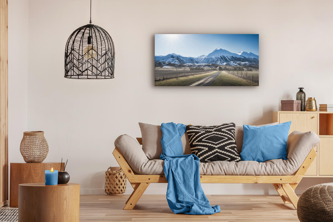 Canvas photo wall art of New Zealand landscape canvas print in lounge setting with a couch, cushions, coffee tables, and pendant light.